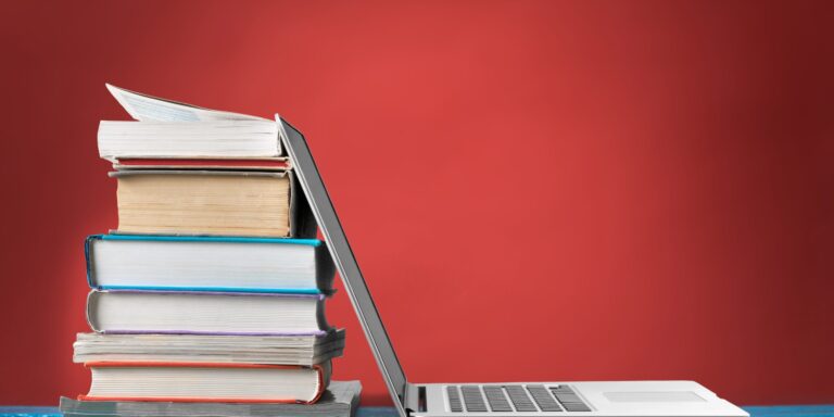 Stack of books with laptop on table